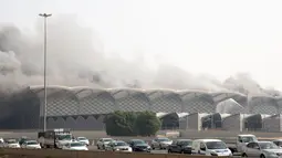 Mobil-mobil melaju saat asap hitam  membumbung menyelimuti gedung Stasiun Kereta Api Cepat Haramain di kota Jeddah, Minggu (29/9/2019). Pasukan Pertahanan Sipil Arab Saudi, dengan dukungan helikopter, harus berjuang selama berjam-jam untuk memadamkan api. (Photo by - / AFP)