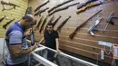 Seorang penjual, Abu Hauraa membantu pembeli memilih senapan di toko senjata berlisensi miliknya di Baghdad, Irak, 24 September 2018. Setelah pelegalan senjata api untuk orang sipil, permintaan akan senjata api semakin meningkat. (AFP/AHMAD AL-RUBAYE)