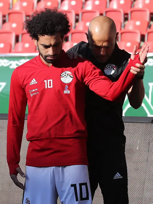 Pemain timnas Mesir Mohamed Salah dibantu tim kesehatan melatih bahunya yang cedera saat pelatihan di stadion Akhmat Arena di Grozny (12/6). Pemain Liverpool ini cedera saat tampil di Final Liga Champions melawan Real Madrid. (AFP Photo/Karim Jaafar)