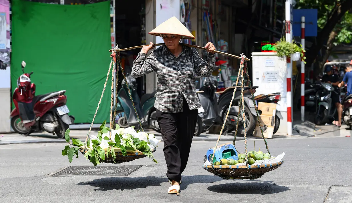 Ribuan pedagang kaki lima, sebagian besar perempuan, di ibu kota Vietnam tidak punya pilihan selain bekerja melewati serangkaian gelombang panas yang melanda bagian utara negara tersebut dalam beberapa minggu terakhir. (Photo by Nhac NGUYEN / AFP)