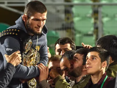 Juara kelas ringan UFC, Khabib Nurmagomedov membawa sabuk juaranya saat disambut oleh para penggemar setibanya di Makhachkala, Rusia, Senin (8/10). Nama Khabib menjadi terkenal setelah dirinya berhasil mengalahkan Conor McGregor. (AFP/Vasily MAXIMOV)