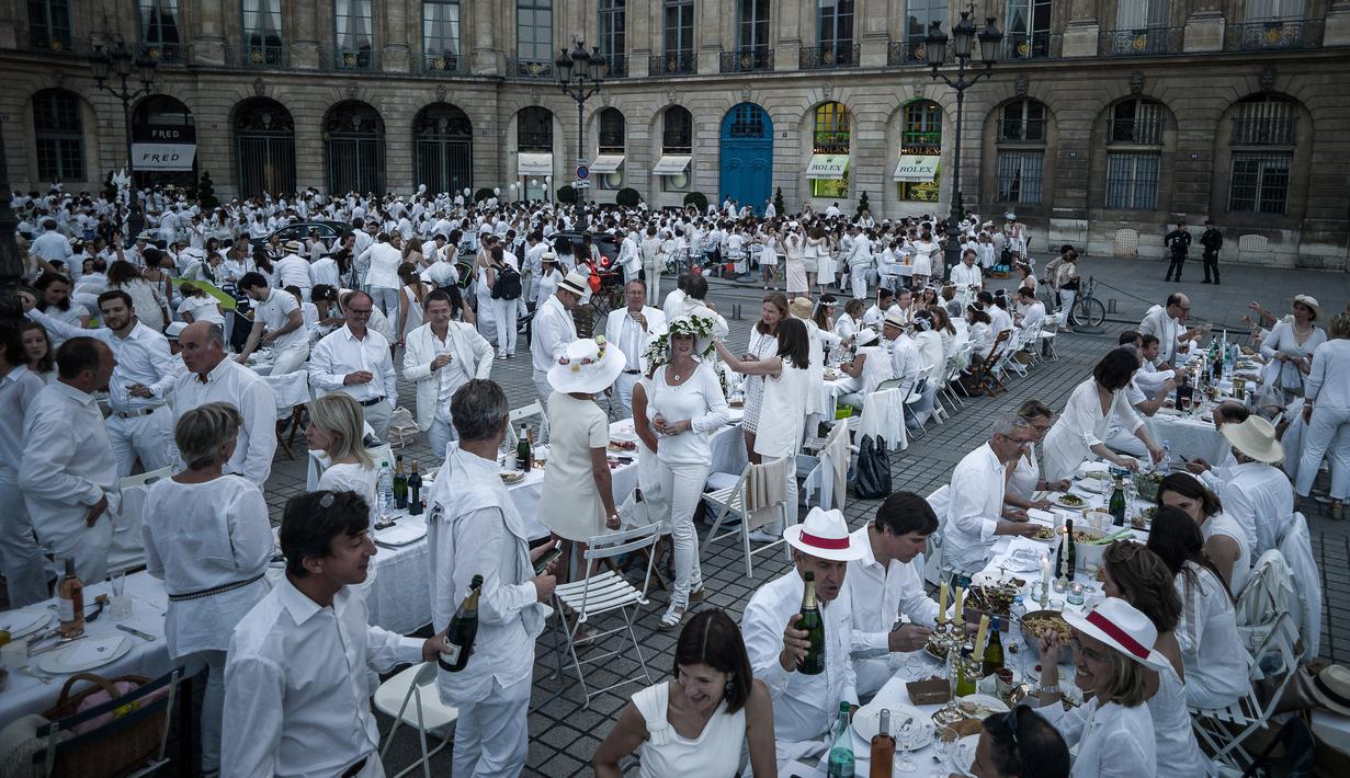 Peserta menikmati makan malam sambil berbincang saat acara 'Diner en blanc' atau 'Makan Malam Putih' di Place Vendome, Paris, Rabu (8/6). Untuk  mendapatkan undangan, peserta harus mengenal seorang anggota organisasi Diner en Blanc. (PHILIPPE LOPE/AFP)