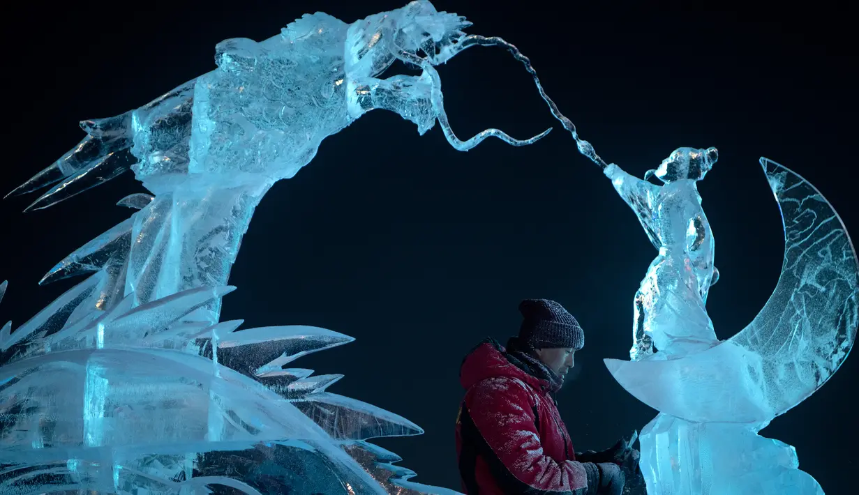 Seorang pemahat es memberikan sentuhan akhir pada patung es di festival Ice and Snow World Harbin, di Harbin, timur laut China, Jumat (3/1/2019). Festival es terbesar dunia ini diadakan untuk menyambut musim dingin yang berlangsung selama satu bulan lebih. (NOEL CELIS/AFP)