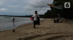 Seorang pria menjajakan dagangannya di sekitar pantai Carita, Pandeglang, Banten, Selasa (18/1/2022). Objek wisata Pantai Carita yang menjadi tempat favorit pengunjung kini tampak sepi seusai gempa beberapa waktu lalui dan juga lantaran naikknya kasus virus covid 19 varian omicron. (Liputan6.com/Joh