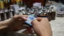 Seorang karyawan memasang label untuk minuman Pfizermeister, minuman yang terinspirasi oleh vaksin virus corona Covid-19, di sebuah bar koktail di George Town di pulau Penang, Malaysia (8/9/2021). (AFP/Mohd Rasfan)