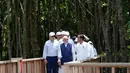 Presiden Amerika Serikat Joe Biden (kiri) dan Perdana Menteri India Narendra Modi (tengah) berjalan bersama Presiden Indonesia Joko Widodo atau Jokowi melewati hutan mangrove Taman Hutan Raya Ngurah Rai di sela-sela pertemuan KTT G20, Denpasar, Bali, Indonesia, Rabu (16/11/2022). Para pemimpin dunia menanam mangrove bersama untuk menekankan peran penting menangani krisis iklim. (AP Photo/Alex Brandon, Pool)