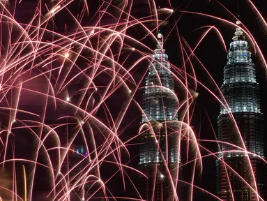 Kembang api menghiasi langit di dekat Menara Kembar Petronas Malaysia saat malam pergantian tahun di Kuala Lumpur, Malaysia. (01/1/2018). Menara Kembar Petronas menjadi salah satu spot para wisatawan menikmati malam tahun baru. (AFP Photo / Mohd Rasfan)