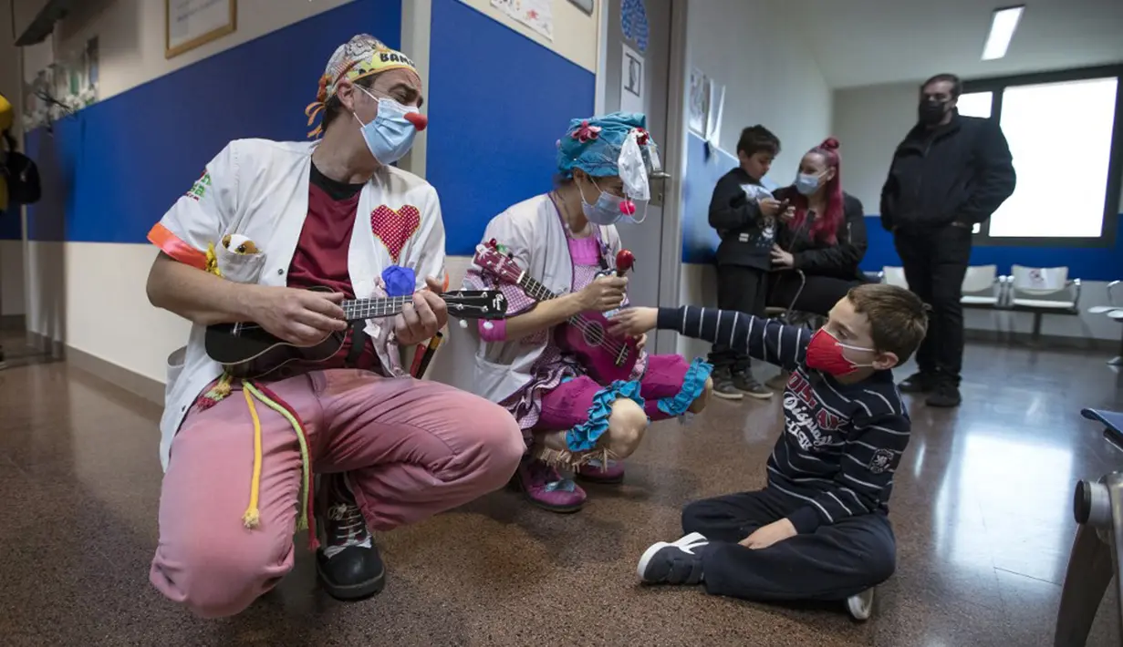 Dua badut dari LSM Sunrise Media (Senyuman Medis) tampil untuk pasien berusia delapan tahun Miquel di sayap anak-anak Rumah Sakit Son Llatzer, Palma de Mallorca, Spanyol, 8 Maret 2021. (JAIME REINA/AFP)