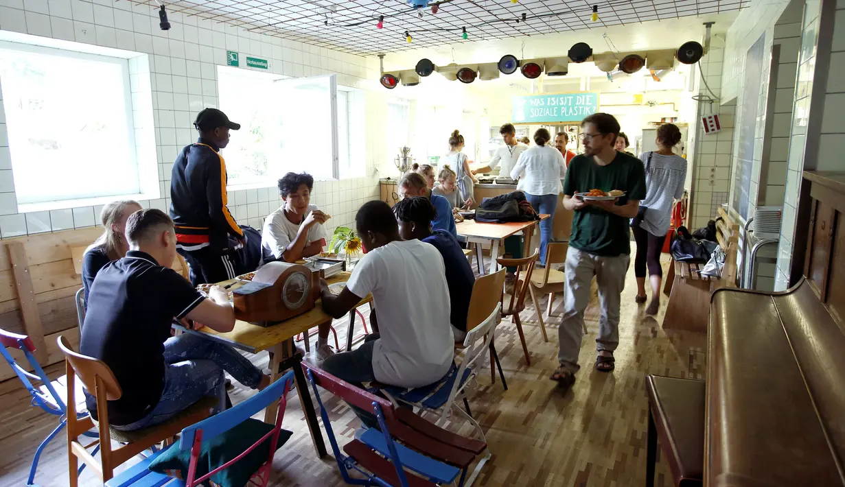 Para imigran dan tamu menyantap makanan diruangan makan di hotel "Grandhotel Cosmopolis", di Augsburg, Jerman, (27/7). Hotel ini dapat menampung sekitar 65 imigran dan wisatawan dari seluruh dunia. (REUTERS/Michaela Rehle)