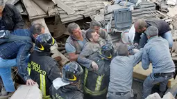Petugas dibantu warga saat berhasil mengeluarkan seorang pria yang tertimbun reruntuhan bangunan akibat gempa di Amatrice, Italia tengah, (24/8). Gempa dengan kekuatan 6,2 SR ini membuat warga panik. (REUTERS/Remo Casilli)