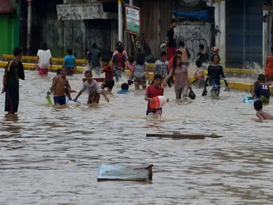 Anak-anak bermain air saat banjir menggenangi Jalan Jatinegara Barat, Jakarta, Kamis (2/1/2020). Hujan yang terjadi kemarin malam membuat Kali Ciliwung meluap ke jalan. (merdeka.com/Imam Buhori)