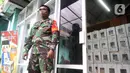Tentara berdiri menjaga kotak hasil rekapitulasi penghitungan suara di TPS tingkat kelurahan di Kecamatan Pamulang, Tangerang Selatan, Banten, Kamis (10/12/2020). Proses rekapitulasi suara ditunda sementara karena terkendala jaringan ke server KPU Pusat down. (merdeka.com/Dwi Narwoko)
