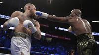 Pukulan jabs Floyd Mayweather Jr. mendarat wajah kanan Conor McGregor pada gelaran Tinju Dunia super welterweight boxing di MGM Arena, Las Vegas, (26/8/2017). Mayweather menang TKO atas McGregor. (AP/Isaac Brekken)