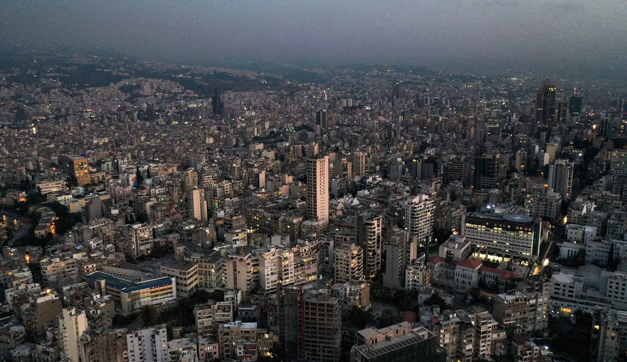 Gambar yang diambil pada 11 Oktober 2021 ini menunjukkan pemandangan udara matahari terbenam di ibu kota Lebanon, Beirut, dengan gedung-gedung dalam kegelapan selama pemadaman listrik. Selama 18 bulan terakhir, Lebanon telah mengalami krisis ekonomi dan kekurangan bahan bakar ekstrem. (AFP)