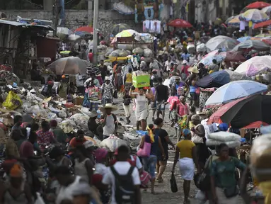 Seorang perempuan membawa baskom dengan barang-barangnya di pasar Petion-Ville di Port-au-Prince, empat hari setelah pembunuhan Presiden Haiti Jovenel Moise, Minggu (11/7/2021). Moïse tewas dibunuh dalam serangan di kediaman pribadinya, pada Rabu 7 Juli 2021 dini hari. (AP Photo/Matias Delacroix)