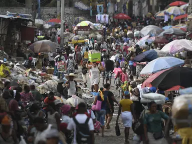 Seorang perempuan membawa baskom dengan barang-barangnya di pasar Petion-Ville di Port-au-Prince, empat hari setelah pembunuhan Presiden Haiti Jovenel Moise, Minggu (11/7/2021). Moïse tewas dibunuh dalam serangan di kediaman pribadinya, pada Rabu 7 Juli 2021 dini hari. (AP Photo/Matias Delacroix)