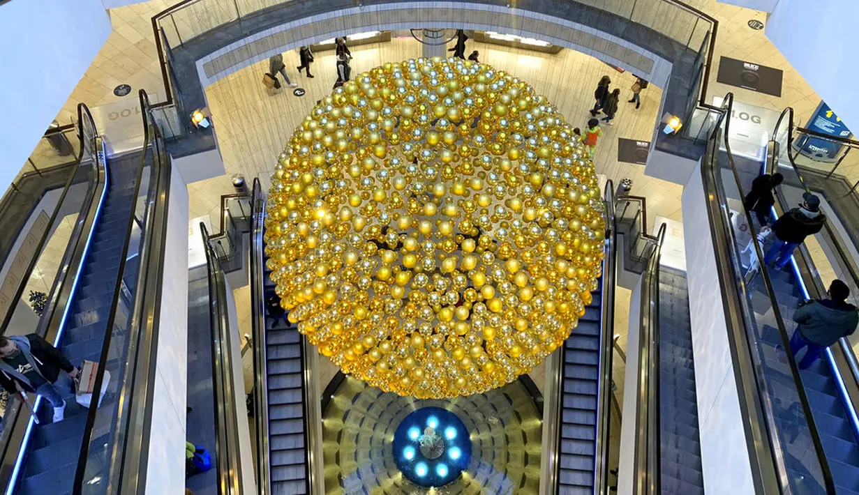 Pelanggan terlihat di eskalator dekat bola Natal raksasa di pusat perbelanjaan, Essen, Jerman, Senin (14/12/2020). Jerman melakukan lockdown nasional pada 16 Desember 2020 untuk memerangi pandemi COVID-19. (AP Photo/Martin Meissner)