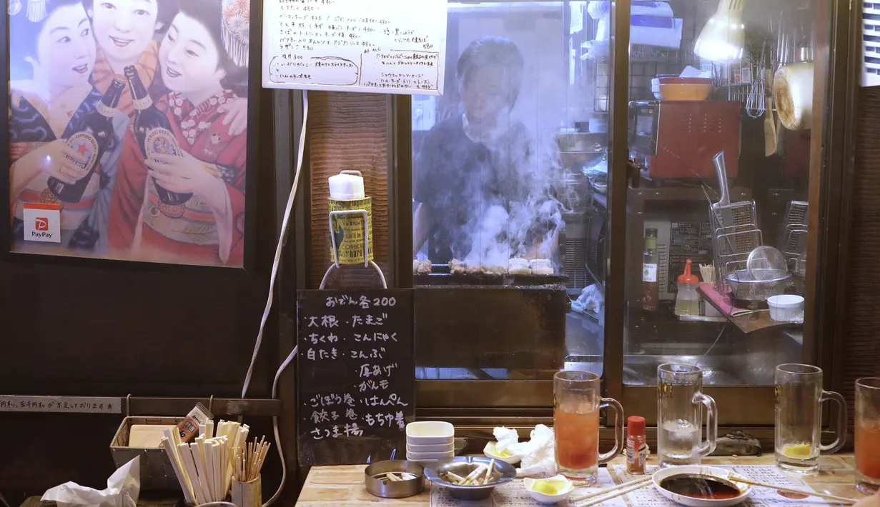 Seorang pemilik bar yakitori menyiapkan makanan di area jalan malam belakang pusat kota Tokyo (4/10/2019). Yakitori terbuat dari potongan daging semua bagian ayam seperti dada, paha , kulit, hati dan jeroan lainnya dan dimasak di atas arang. (AP Photo/Mark Baker)