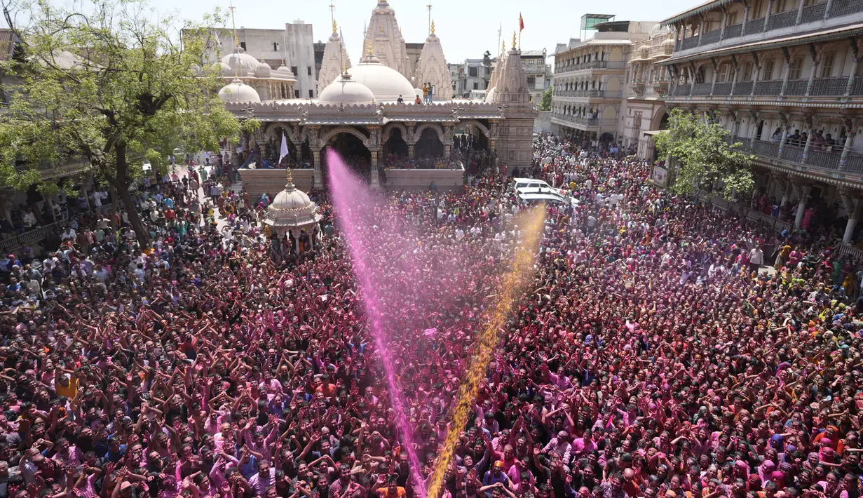 Umat Hindu bersorak saat bubuk berwarna dan air disemprotkan selama perayaan Festival Holi di kuil Kalupur Swaminarayan di Ahmedabad, India (18/3/2022).  Holi, festival warna Hindu, juga menandai datangnya musim semi. (AP Photo/Ajit Solanki)