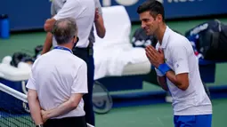 Petenis Serbia, Novak Djokovic berbicara dengan wasit setelah hantaman bolanya mengenai hakim garis saat kehilangan poin dari Pablo Carreno Busta (Spanyol) pada putaran keempat US Open 2020, di Flushing Meadows, (6/9/2020). Djokovic pun didiskualifikasi dari AS Terbuka 2020. (AP Photo/Seth Wenig)