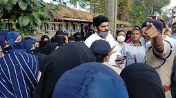 Orang tua siswi India yang dilarang masuk ke ruang kelas mereka karena mengenakan jilbab berdebat dengan seorang petugas polisi di luar gedung kampus di Udupi, India, Jumat, 4 Februari 2022. (Bangalore News Photos via AP)