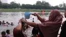 Seorang anak saat dikeramas di bantaran sungai Cisadane di kawasan Babakan, Kota Tangerang, Jumat (1/4/2022). Keramas bersama merupakan tradisi warga yang berada dikawasan tersebur sebagai simbol membersihkan diri untuk menyambut bulan Ramadhan. (Liputan6.com/Angga Yuniar)