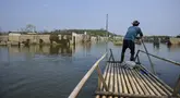 Seorang pria mengendalikan rakit bambunya di kawasan Bendungan Karian yang mengering di Kampung Somang, Lebak, Banten, Kamis (30/7/2026). (AFP/ Bay Ismoyo)