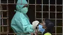 Seorang petugas kesehatan mengumpulkan sampel usap dari seorang gadis untuk menguji virus Corona Covid-19 di daerah kumuh di Hyderabad (23/9/2020). (AFP/Noah Seelam)