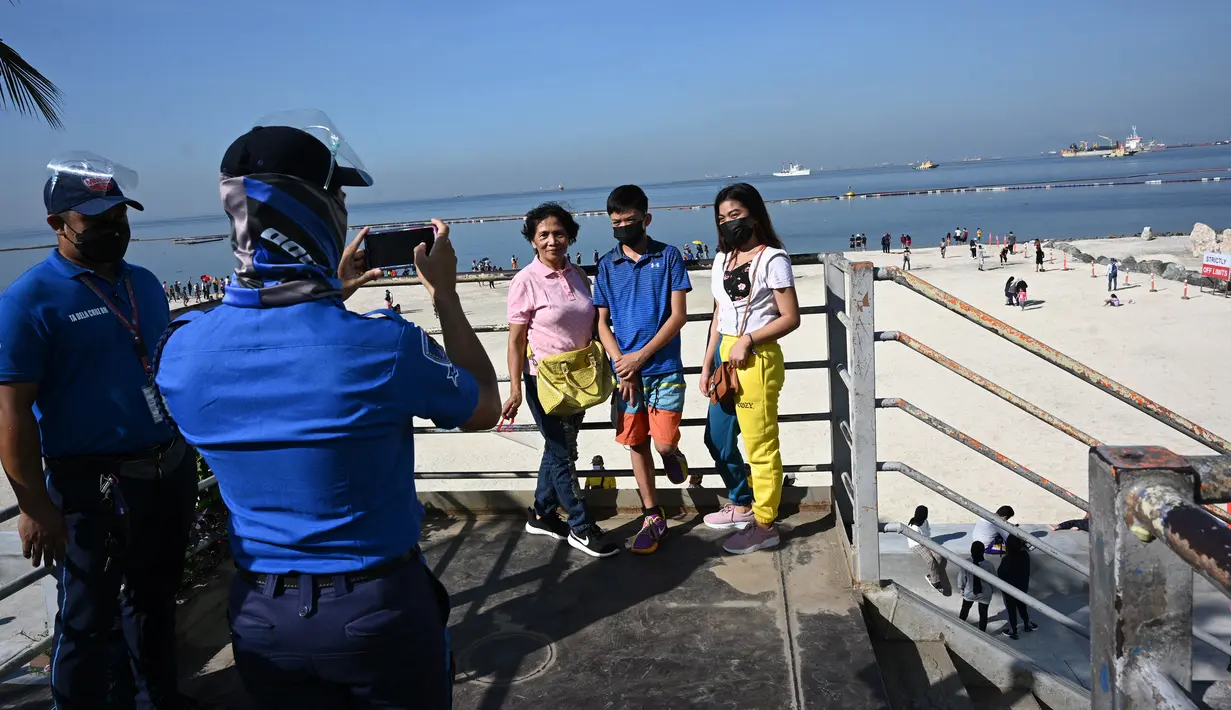 Warga berfoto di jembatan penyeberangan yang menghadap ke Manila baywalk dolomite beach di sepanjang boulevard Roxas, kota Manila, Filipina pada Minggu (17/10/2021). Sehari sebelumnya, pihak berwenang melonggarkan pembatasan karantina di ibu kota negara itu. (Ted ALJIBE / AFP)