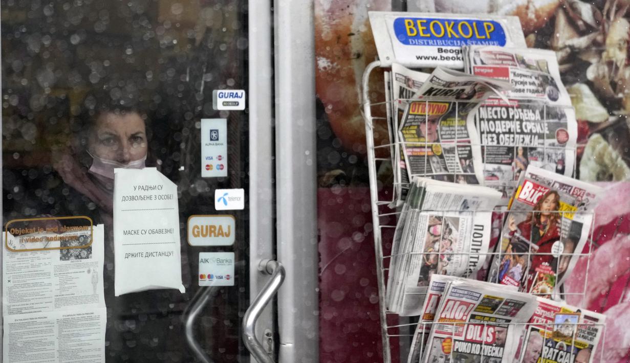 Seorang wanita melihat melalui jendela toko selama badai salju di Beograd, Serbia, Minggu (12/12/2021). Hujan salju lebat pada Minggu menghambat lalu lintas, membatalkan penerbangan di bandara utama ibu kota Serbia, dan mengganggu transportasi umum (AP Photo/Darko Vojinovic)