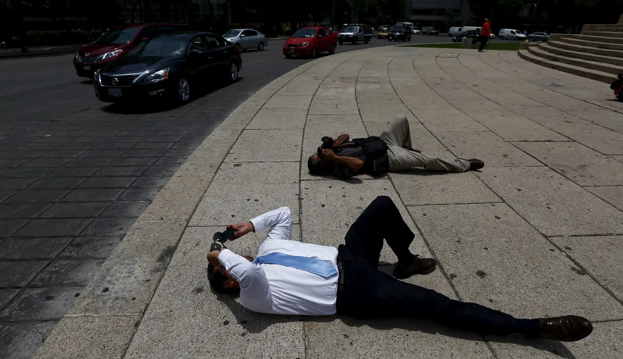 Sejumlaha orang melihat fenomena ' Halo Matahari' dengan posisi tertidur di jalanan untuk mengabadikannya di langit Mexico City, Kamis (21/5/2015). (REUTERS/Edgard Garrido)
