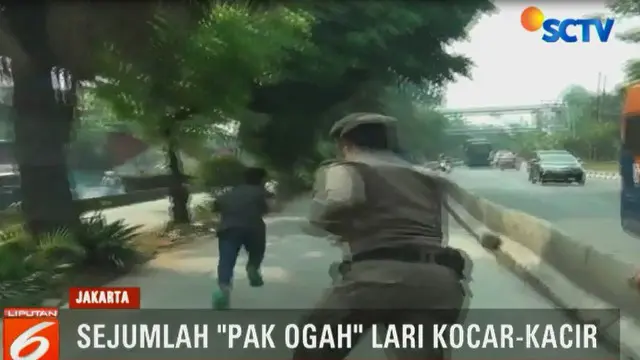 salah seorang Pak Ogah tampak jatuh bangun dan nekat berlari melintasi lalu lintas kendaraan, guna menghindari petugas.