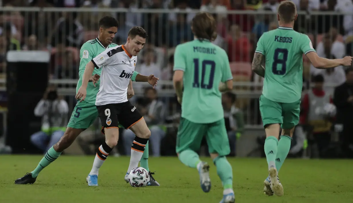 Penyerang Valencia, Kevin Gameiro membawa bola dari kawalan bek Real Madrid, Raphael Varane pada pertandingan semifinal Piala Super Spanyol di stadion King Abdullah di Jiddah, Arab Saudi, Rabu, (8/1/2020). Hasil ini membua Real Madrid melaju ke final Piala Super Spanyol. (AP Photo/Hassan Ammar)