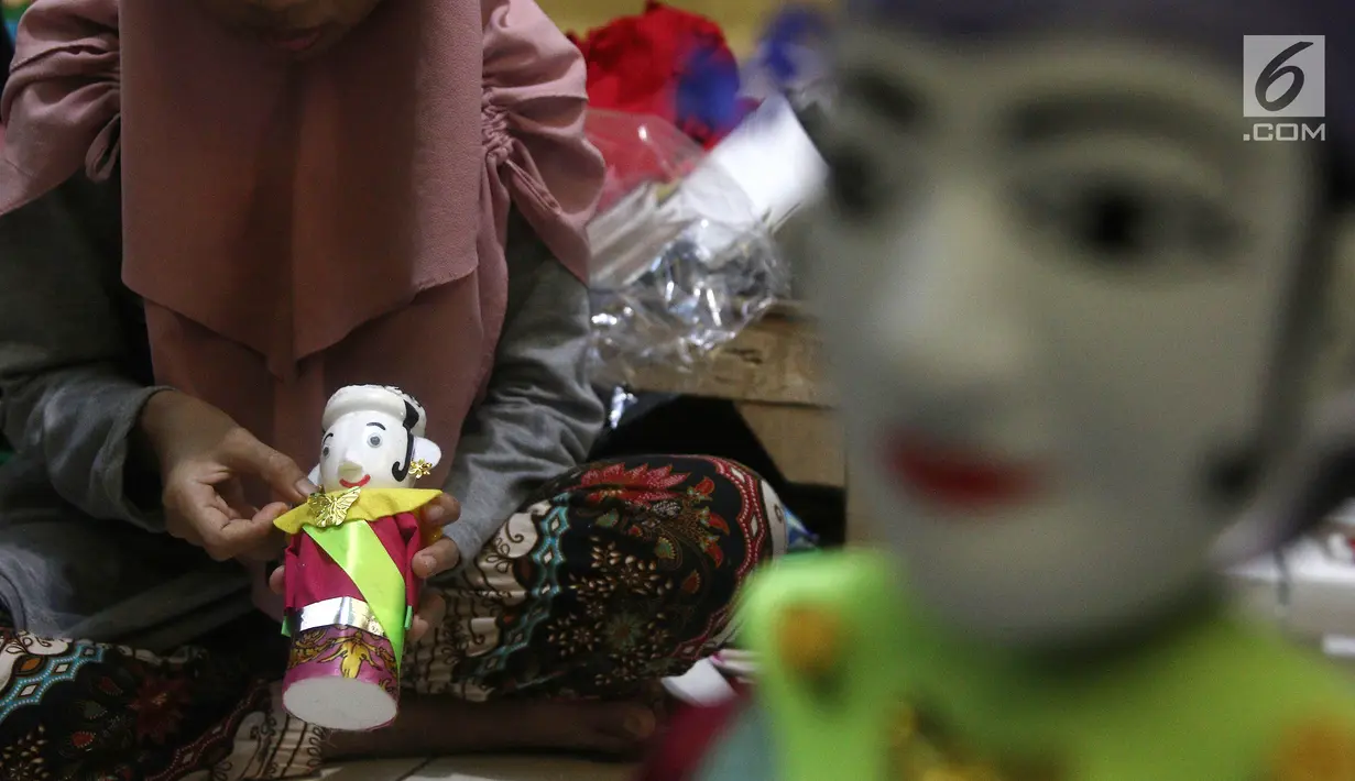 Perajin, membuat baju untuk miniatur ondel-ondel dari botol plastik di rumah produksi Kramat Jati, Jakarta, Rabu (28/11). Miniatur yang terbuat dari plastik memproduksi 50-80 buah dengan omset 5-8 Juta perbulan. (Liputan6.com/Herman Zakharia)