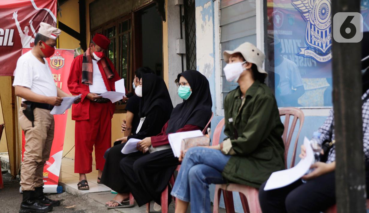 Petugas kepolisian berpakaian pejuang jaman dulu mengecek surat vaksin Covid-19 milik warga di Polsek Pasar Rebo, Jakarta, Selasa (17/8/2021). Para petugas berkostum pejuang jaman dulu memeriahkan HUT ke-76 Republik Indonesia. (Liputan6.com/Angga Yuniar)