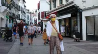 Orang-orang dengan masker berjalan di jalur pejalan kaki di Saint Jean de Luz, Prancis barat daya, Selasa (27/7/2021). Otoritas setempat di Prancis memberlakukan kembali mandat masker dan pembatasan COVID-19 lainnya karena penyebaran varian delta menyebabkan rawat inap meningkat lagi. (AP/Bob Edme)