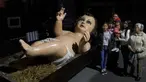 Anggota keluarga berpose dekat patung bayi Yesus raksasa di Mexico City, Meksiko, Senin (23/12/2019). Patung tersebut dipersiapkan untuk menyambut malam Natal. (AP Photo/Marco Ugarte)