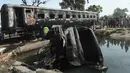 Sebuah truk hangus terbakar usai kecelakaan antara kereta penumpang dan kereta tangki minyak di Distrik Sheikhupura, Punjab, Selasa (28/3). Akibat kejadian tersebut sejumlah gerbong kereta dan kendaraan hangus terbakar. (AFP Photo / Ludovic Marin)