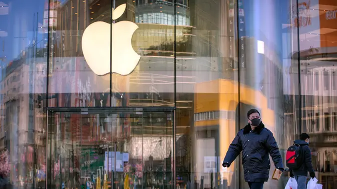 Warga berjalan melewati Apple Store yang tutup di Beijing, China, Selasa (4/2/2020. Belum diketahui bagaimana nasib Apple Store lainnya yang sudah ditutup sejak 1 Februari lalu lantaran wabah virus corona. (AP Photo/Mark Schiefelbein)