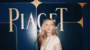 Ella Richards tampil bersinar dalam Swinging Sautoir dengan zamrud hijau, berlian putih, dan pelat jam malachite. Kalung panjang ini lengkapi gaun putih dengan cutout di bagian samping [Piaget]