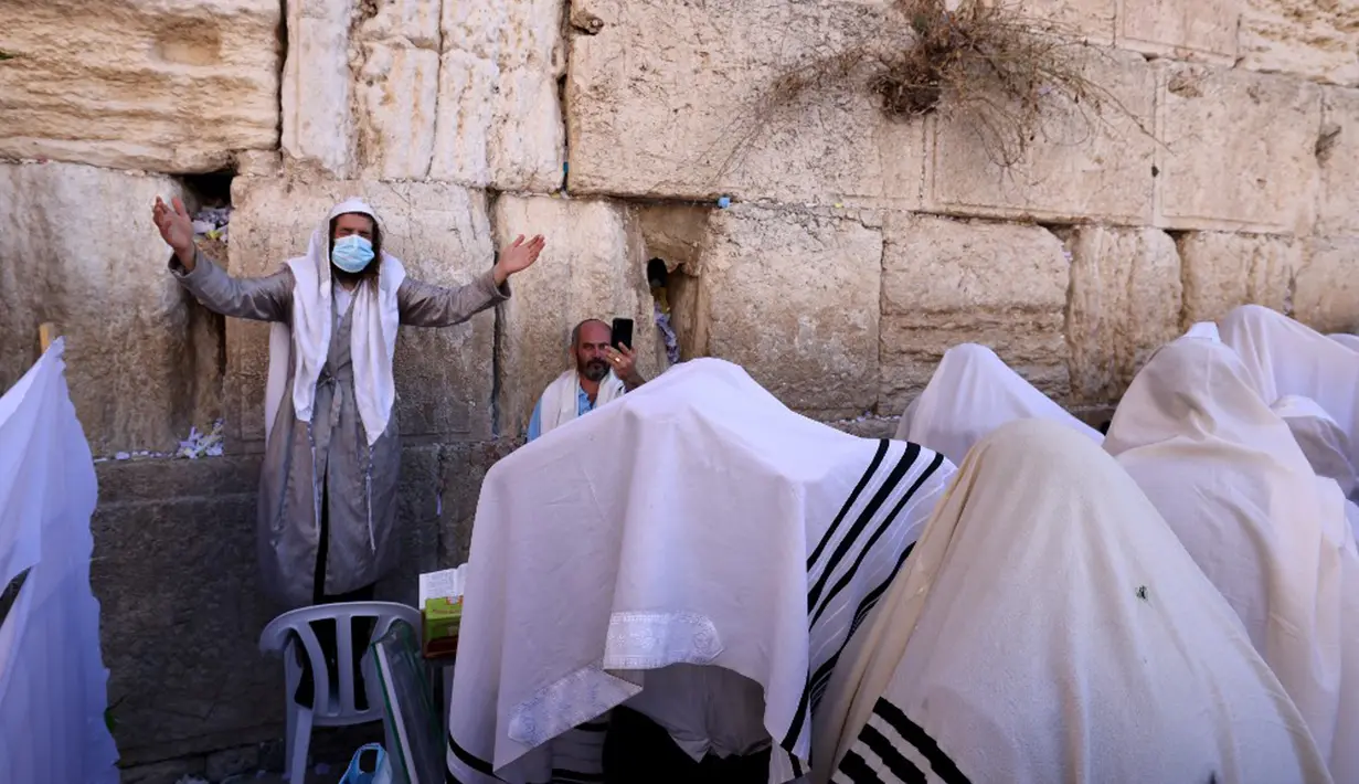Umat Yahudi memanjatkan doa saat memperingati Hari Raya Sukkot di Tembok Barat, Kota Tua Yerusalem, 22 September 2021. Sukkot adalah hari raya untuk memperingati eksodus bangsa Israel dari Mesir sekitar 3200 tahun yang lalu. (Emmanuel DUNAND/AFP)