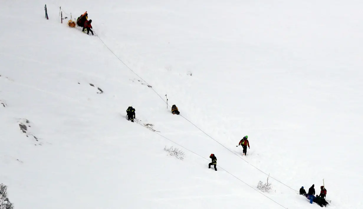 Petugas mengevakuasi korban helikopter yang jatuh di kawasan ski Campo Felice, Italia, Selasa (24/1). Berdasarkan laporan awal helikopter tersebut jatuh usai menjemput seseorang yang terluka akibat kecelakaan ski. (AP Photo)