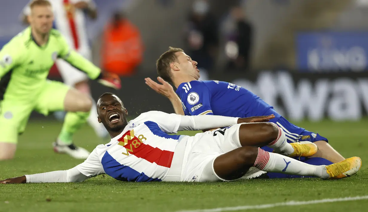 Striker Crystal Palace, Christian Benteke (kiri) dan bek Leicester City, Jonny Evans terjatuh saat perebutan bola dalam laga lanjutan Liga Inggris 2020/2021 pekan ke-33 di King Power Stadium, Leicester, Senin (26/4/2021). Crystal Palace kalah 1-2 dari Leicester. (AP/Andrew Boyers/Pool)