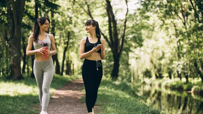 Dua orang perempuan sedang berolahraga dengan berjalan kaki di taman (Foto Dok: Freepik/senivpetro)