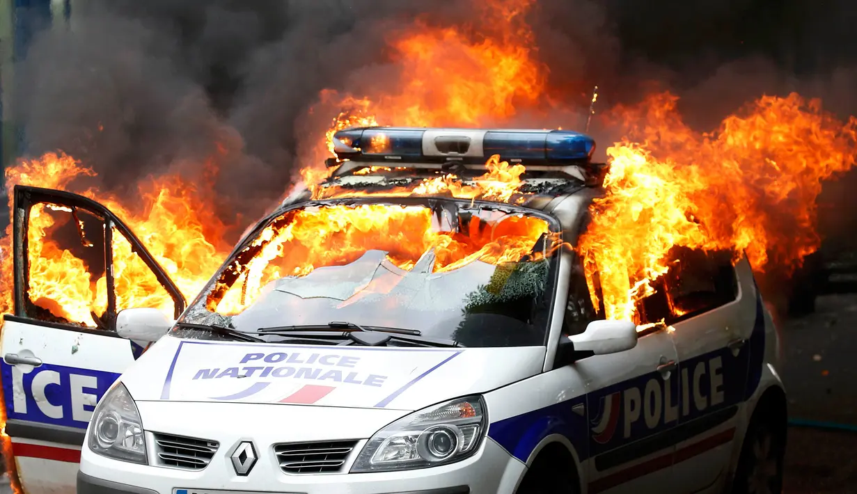Sebuah mobil polisi terbakar saat demonstrasi buruh di Paris, Prancis (18/5). Demo buruh tersebut menentang kekerasan polisi dan melawan reformasi hukum yang berakhir bentrok dengan polisi. (REUTERS / Charles Platiau)
