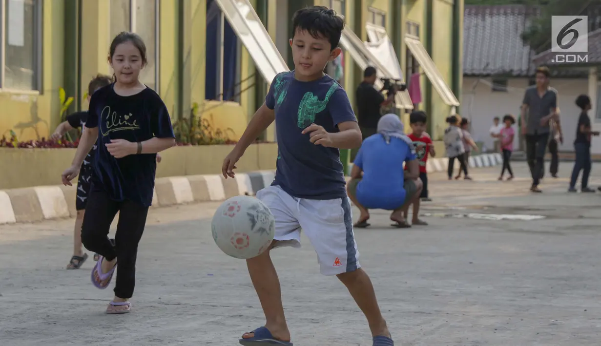 Anak-anak pencari suaka bermain sepak bola di halaman bekas Markas Kodim di Kalideres, Jakarta, Selasa (16/7/2019). Sebelumnya, para pencari suaka dari berbagai negara berkonfilk ini tinggal di pinggir jalan dan trotoar di kawasan Kebon Sirih, Jakarta. (Liputan6.com/Helmi Fithriansyah)