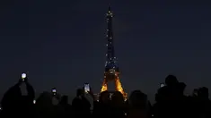 Warga memotret Menara Eiffel yang diterangi warna bendera Ukraina di Paris (25/2/2022). Pasukan Rusia menyerang ibu kota Ukraina pada Jumat (25/2) dengan tembakan dan ledakan dalam invasi ke negara demokratis yang memicu kekhawatiran perang yang lebih luas di Eropa. (AP Photo/Adrienne Surprenant)