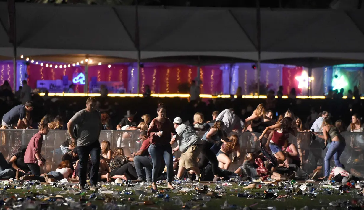Sejumlah pengunjung berlindung saat festival musik Route 91 Harvest country setelah aksi penembakan di Las Vegas, Nevada (1/10). Pelaku penembakan disebut menembak seorang petugas keamanan dan polisi setempat. (David Becker/Getty Images/AFP)