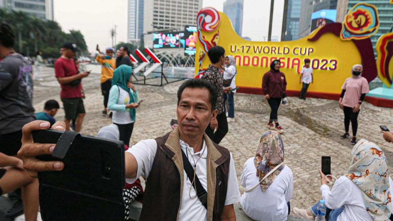 Di sisi lain, masyarakat antusias berswafoto di depan papan promosi Piala Dunia U-17 saat Car Free Day di kawasan BUndaran HI, Jakarta, Minggu (15/10/2023).<br>