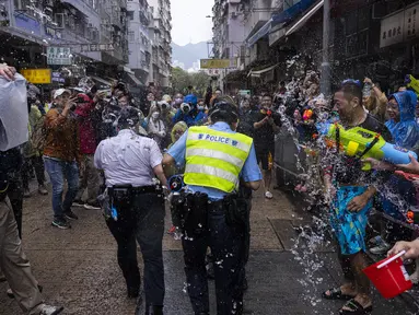 Orang-orang yang bersuka ria memercikkan air ke petugas polisi saat perayaan festival Songkran di Hong Kong, Minggu, 9 April 2023. (AP Photo/Louise Delmotte)